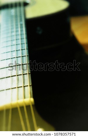 close up vintage photo of acoustic guitar neck with blurred background