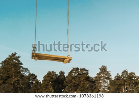 homemade wooden swing against the blue sky and trees,
