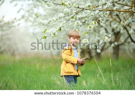 Blonde boy in a blooming garden