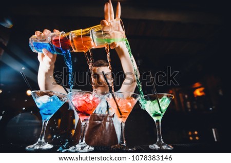 Barman mixes cocktail show with colorful alcoholic cocktails at bar counter. Royalty-Free Stock Photo #1078383146
