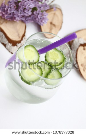 Detox flavored water with cucumber on white background with lilac and wood decoration. Healthy food concept.  Refreshing summer homemade cocktail. Copy space. No sharpen. 