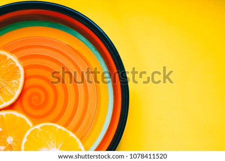 Top view of a plate with sliced orange on an yellow pastel background. Flat lay with copy space for text