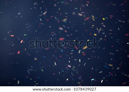 Confetti fired on air during a festival at night. Image ideal for backgrounds. Multicolor are the confetti in the picture. The sky as background is black