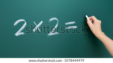 Hand writing math simple equation on blackboard