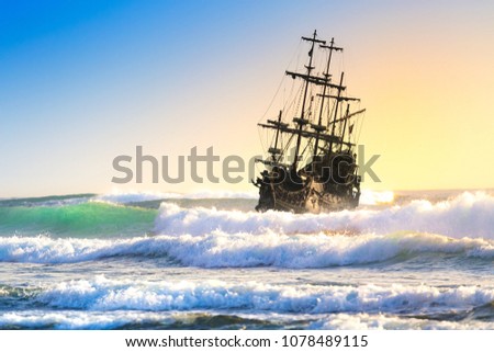Pirate ship at the open sea at the sunset