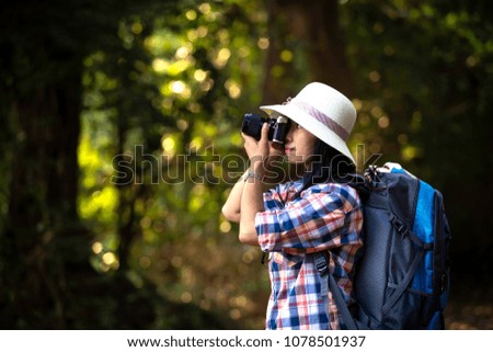 Lady in white hat taking pictures, woman with vintage camera taking in a forest