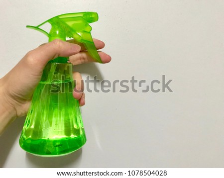 A Hang Holding a Green Foggy Spray for Gardening or Ironing  on a White Background