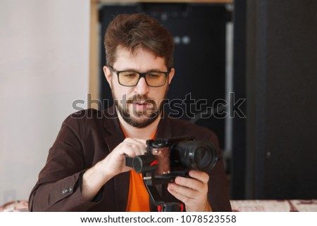 Photographer with glasses and a beard shoots at the camera