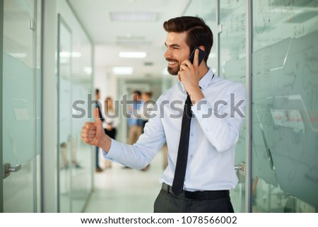 Young businessman on the phone with a group of people behind out of focus
