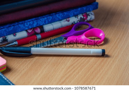 Notepad with scissors with handles and accessories on the table, stationery, education, business