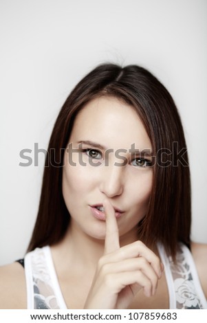Woman making a keep it quiet sign with her finger shot on white background