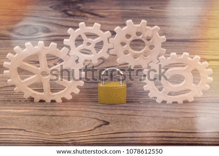hinged closed lock, gears on a wooden background. safety, reliability of the mechanism.