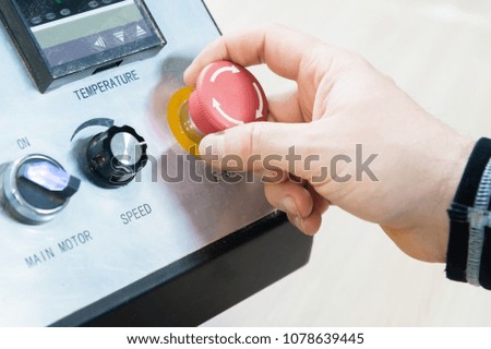 Close-up of a man's hand on a red button on the control panel. Emergency stop or start of equipment and production