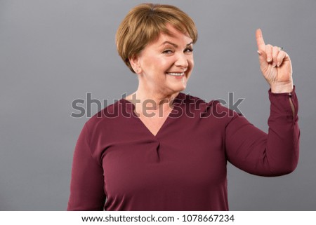 Bright idea. Positive cheerful woman pointing up with her finger while having a great idea