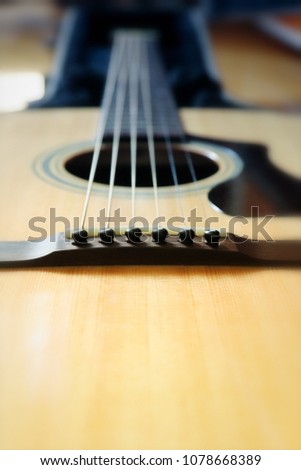 Close up photo of details on acoustic guitar with accent on strings. Vintage colours and blurred background