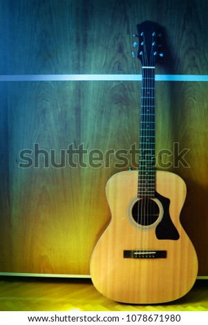 Pphoto of acoustic guitar laid against wooden background. Horizontal photo with guitar on right side. Vintage colors and artistic atmosfere.