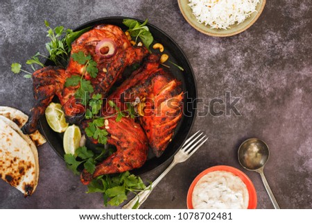 Tandoori Chicken whole with naan, raita and pilau rice, top view, blank space Royalty-Free Stock Photo #1078702481