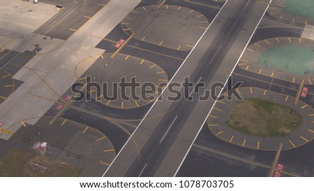 AERIAL, CLOSE UP: Flying close above large asphalt and concrete piste on big modern international airport near busy turnpike highway. Runway designator markings, numbering and signs on the track