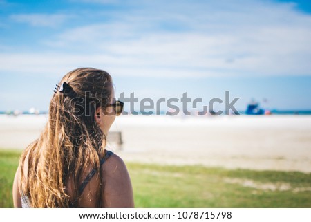 Girl on holiday walks onto Siesta Key Beach, Florida on a Sunny day, with green and blue tones