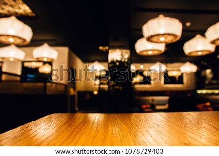 Blurred background of a cozy cafe restaurant and wooden table for the goods.