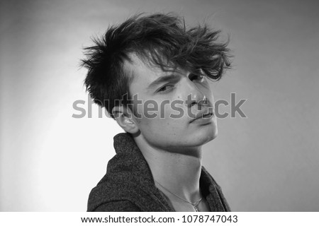 Man face close up. Beautiful young guy with long forelock, quiff. Black and white handsome male portrait on grey background. Royalty-Free Stock Photo #1078747043