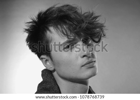 Man face close up. Beautiful young guy with long forelock, quiff. Black and white handsome male portrait on grey background. Royalty-Free Stock Photo #1078768739