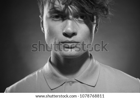 Man face close up. Beautiful young guy with long forelock, quiff. Black and white handsome male portrait on grey background. Royalty-Free Stock Photo #1078768811