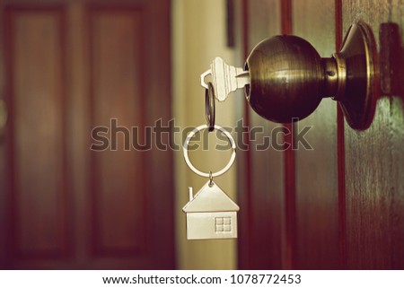 Home key with house keyring on keyhole of wood door