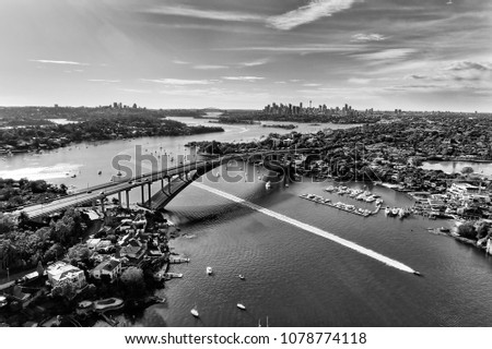 High-contrast black white aerial view over Parramatta river and Gladesville bridge on Victoria road towards Sydney city CBD skyline .
