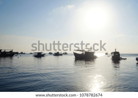 Sunsettng at Koh Tao, Thailand with shadowed boats, calm ocean and blue water