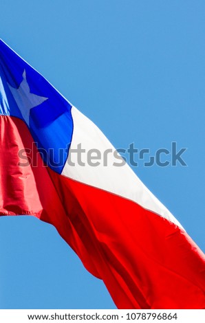 Chile flag waving on bright sunny day. Isolated Chilean flag with blue background.
