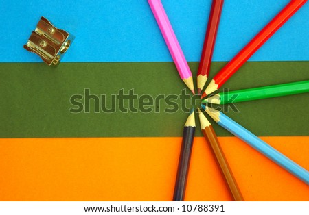 Various pencils and a sharpener on a colored background