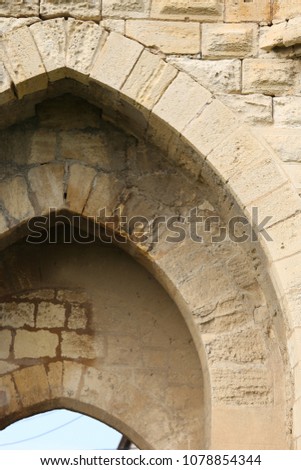 Close up outdoor view of the arch of a rampart entrance door. Opening in an old stone wall with three arcades. Abstract architectural image of part of a medieval fortification. Rough textured surface.
