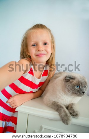 Adorable little girl with her pet cat at home. Love between kid and pet