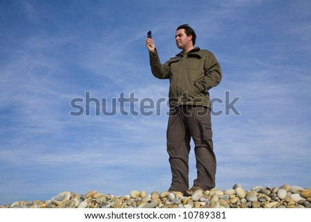 Young man at beach taking photo on the phone