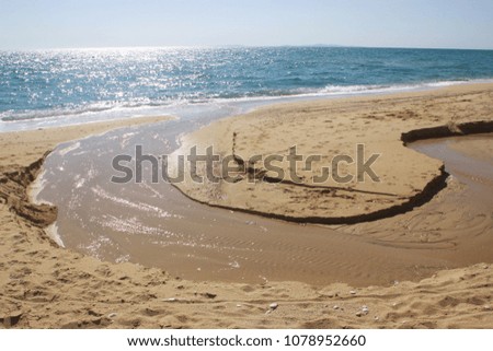 Small creek flows into the ocean through a sandy beach