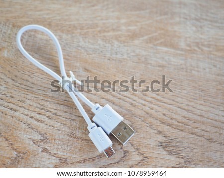Micro usb white cable put on wooden table, it is small and short For portability Connect to charger with backup battery. Or use the data. With computer