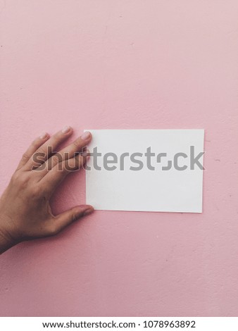 Hand and white paper at pink wall background