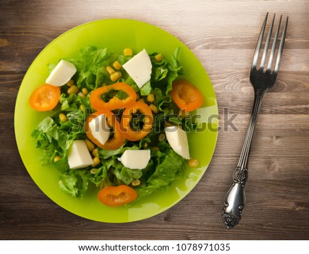  salad of cheese, lettuce, corn, pepper on a wooden background. Vegetarian salad on a plate. Vegetarian salad top view
