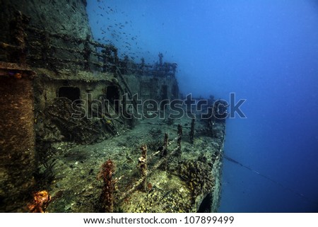 The sunken shipwreck Eagle in the Florida Keys. A ship laying in the sand on it's side with the wreck broken in half. Blue water surrounding coral covered boat. with a lot of fish and animals. Royalty-Free Stock Photo #107899499