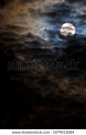 The moon behind the dark clouds