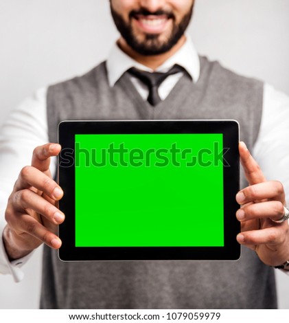 Bearded smiling businessman holds tablet computer with green screen on isolated white background