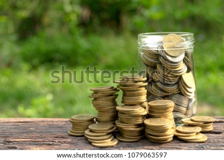 Coins in glass jar and be side on wooden in nature it's for business,finance,save money,