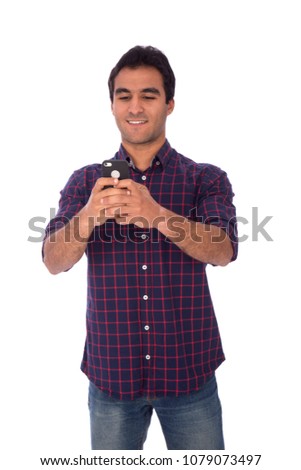 Handsome young man wearing a casual outfit and holding his phone chatting with friends, isolated on white background.