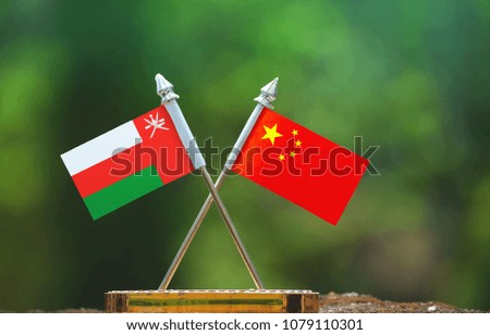China and Oman small flag with blur green background