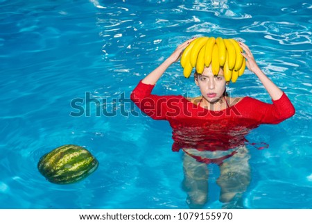 Girl holding watermelon and banana in the blue pool, instagram style. Tropical fruit diet. Summer holiday idyllic.