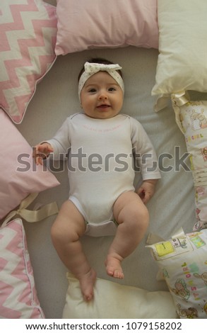 beautiful baby girl with a headband, newborn lying on bed smiling 