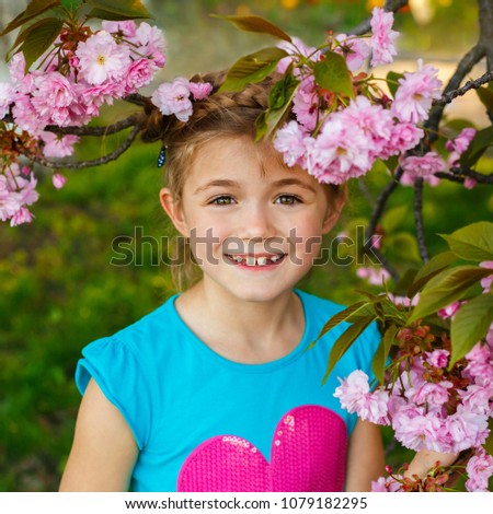 Pretty little girl in blossom cherry garden on beautiful spring day