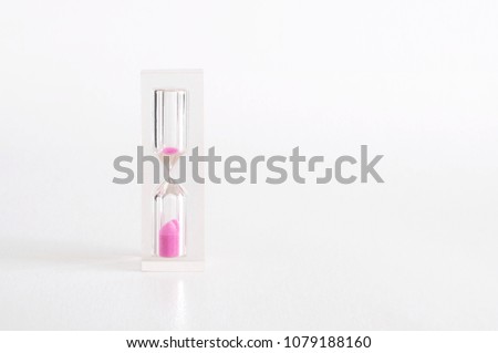 Transparent hourglass with pink sand on white background. Time concept. Empty space for your text on the right