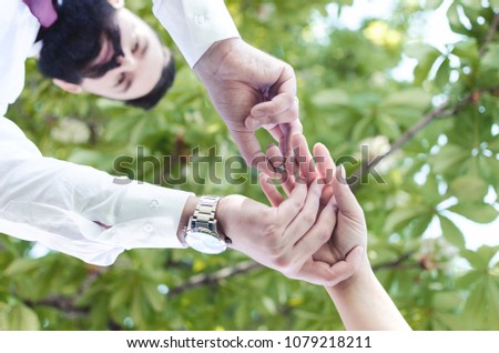 Picture of man putting engagement silver ring on woman hand, outdoor